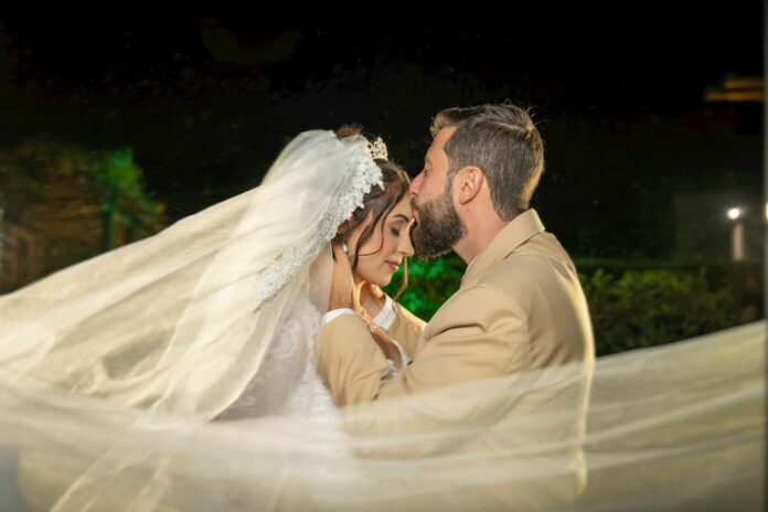 Romantycznie udekorowana sypialnia, gotowa na wyjątkową pierwszą noc poślubną, z delikatnym światłem i płatkami róż