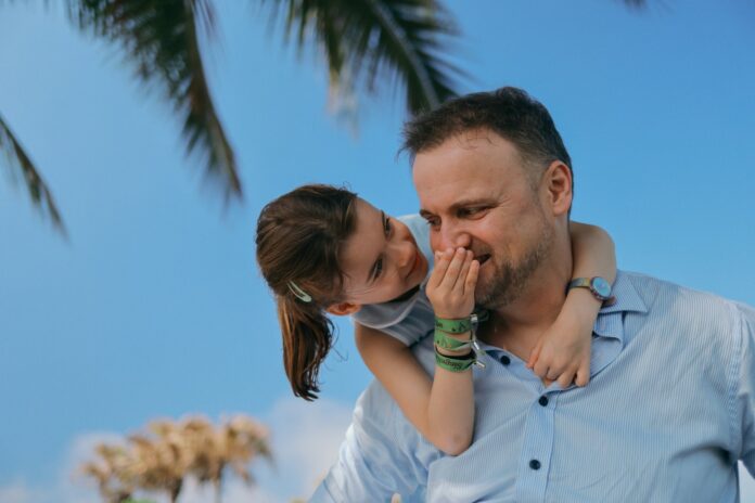 Ojciec z uśmiechniętą córką wspólnie grają w planszówki, budując więź ojca z córką w radosnej atmosferze relaksu