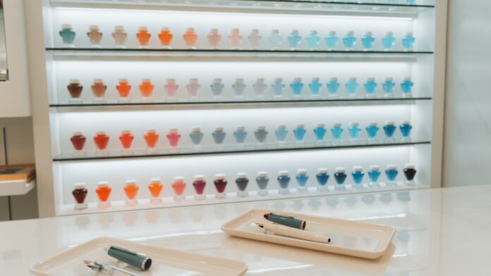 Kolorowe narzędzia kaligraficzne oraz piękne, ozdobne litery na stole, zachęcające do odkrywania sztuki kaligrafii