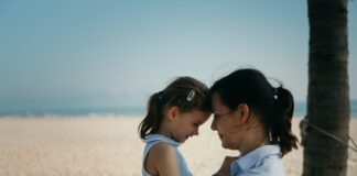 Jak zadbać o relację z córką po rozwodzie rodziców Ciepła relacja z córką po rozwodzie, ojciec przytula ją podczas wspólnego spędzania czasu w parku pełnym zieleni.