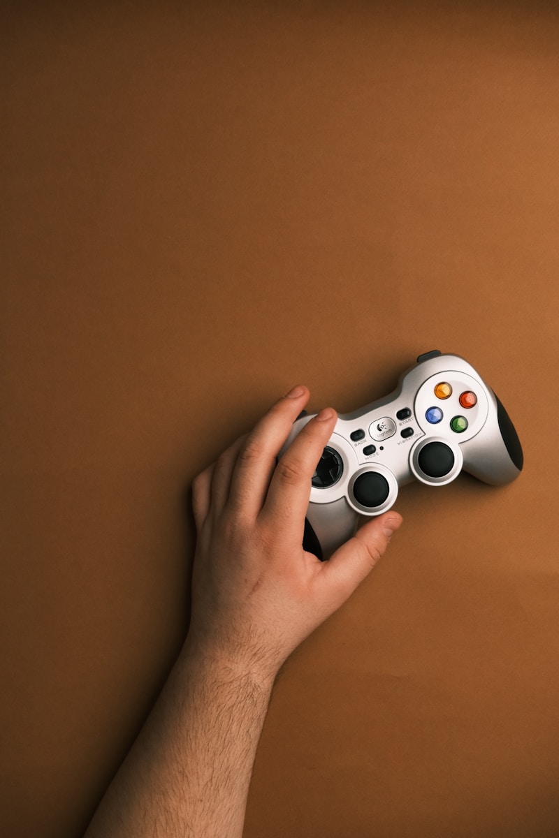 Na zbliżeniu widać ręce nastolatka trzymającego kontroler do gier, wskazując na rosnące uzależnienia od gier video